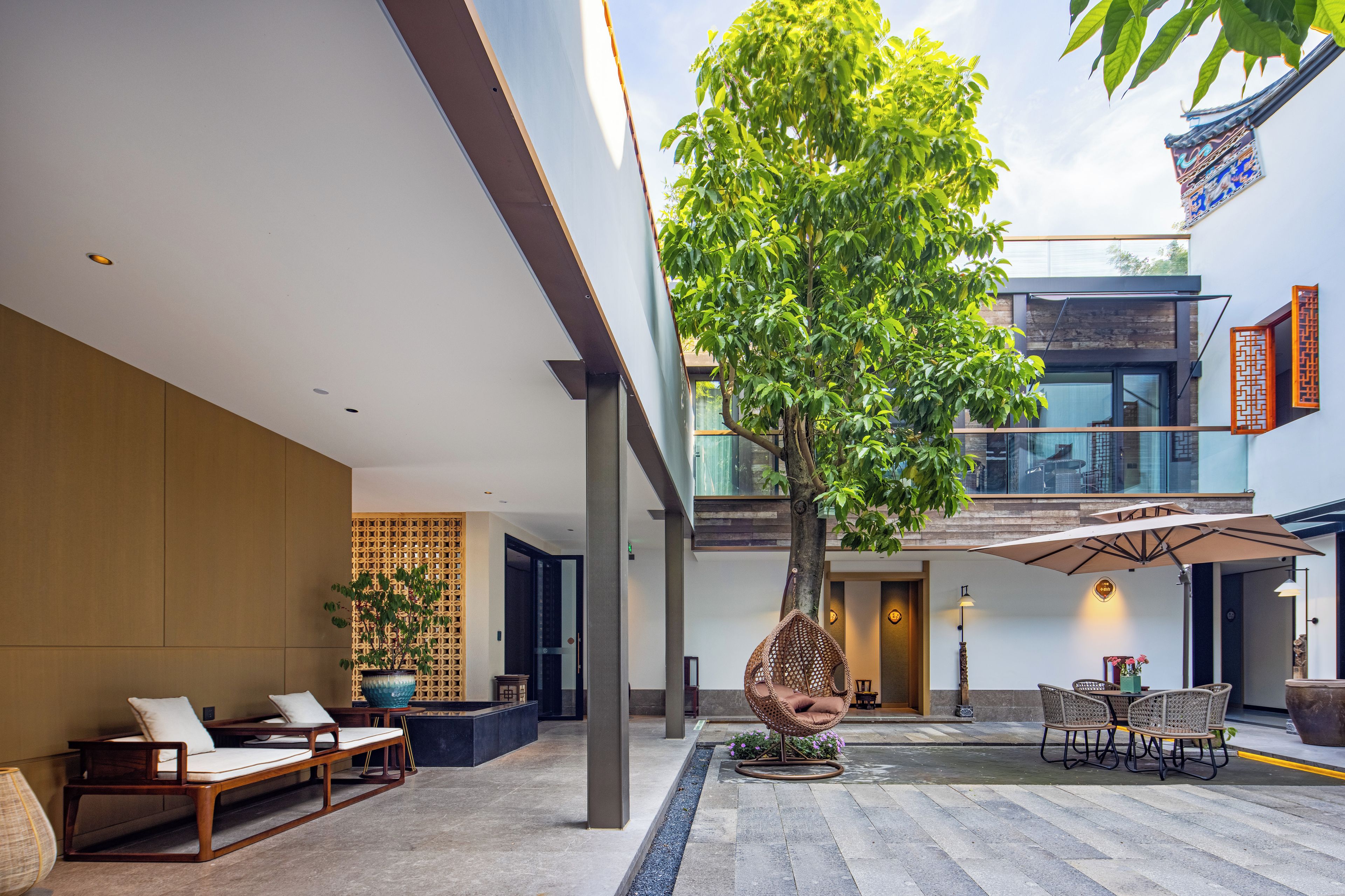 Un interior moderno con un árbol grande, una zona de estar y vistas al exterior.