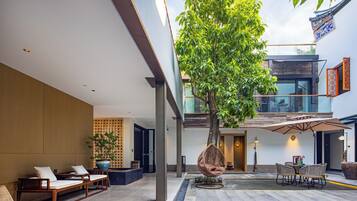 Un interior moderno con un árbol grande, una zona de estar y vistas al exterior.