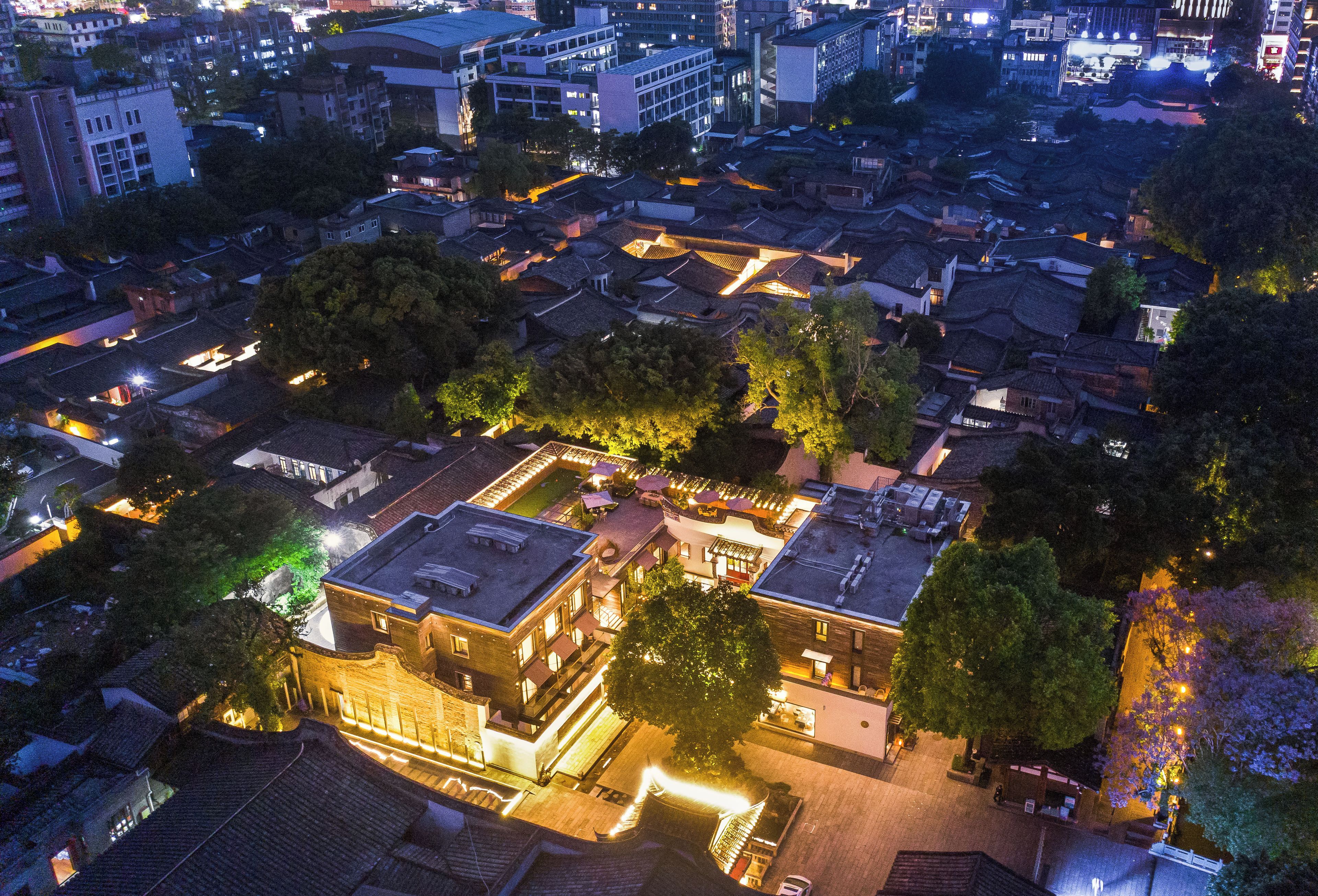 Vista aérea de uma cidade histórica com edifícios tradicionais, um pátio central e construções modernas ao redor.