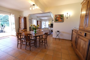A dining area with a round wooden table, chairs, and a vase of sunflowers. - Air-co villa, Luberon views, heated pool, sleeps 8 (La Motte-d´Aigues)