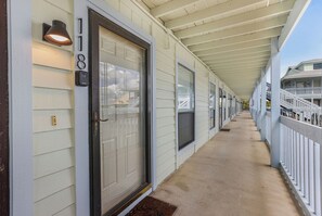 A covered corridor with a door, a mailbox, and a railing on the right. - Gulf Shores Cozy Getaway: 1BR Condo Pool Access/5 Minute Walk to Beach (Gulf Shores)