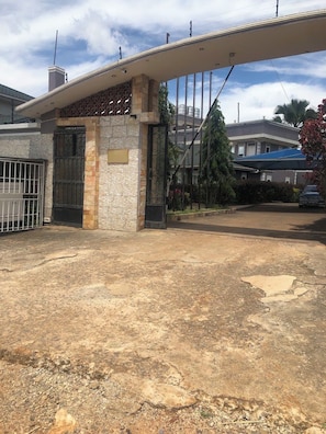 A gated entrance with a stone facade, a metal gate, and a clear sky.