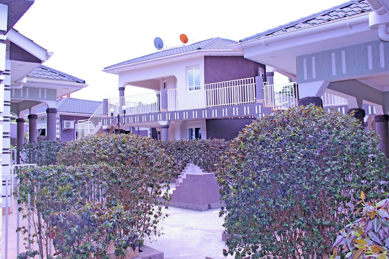 A residential building with a balcony, satellite dishes, and a staircase leading to the entrance.