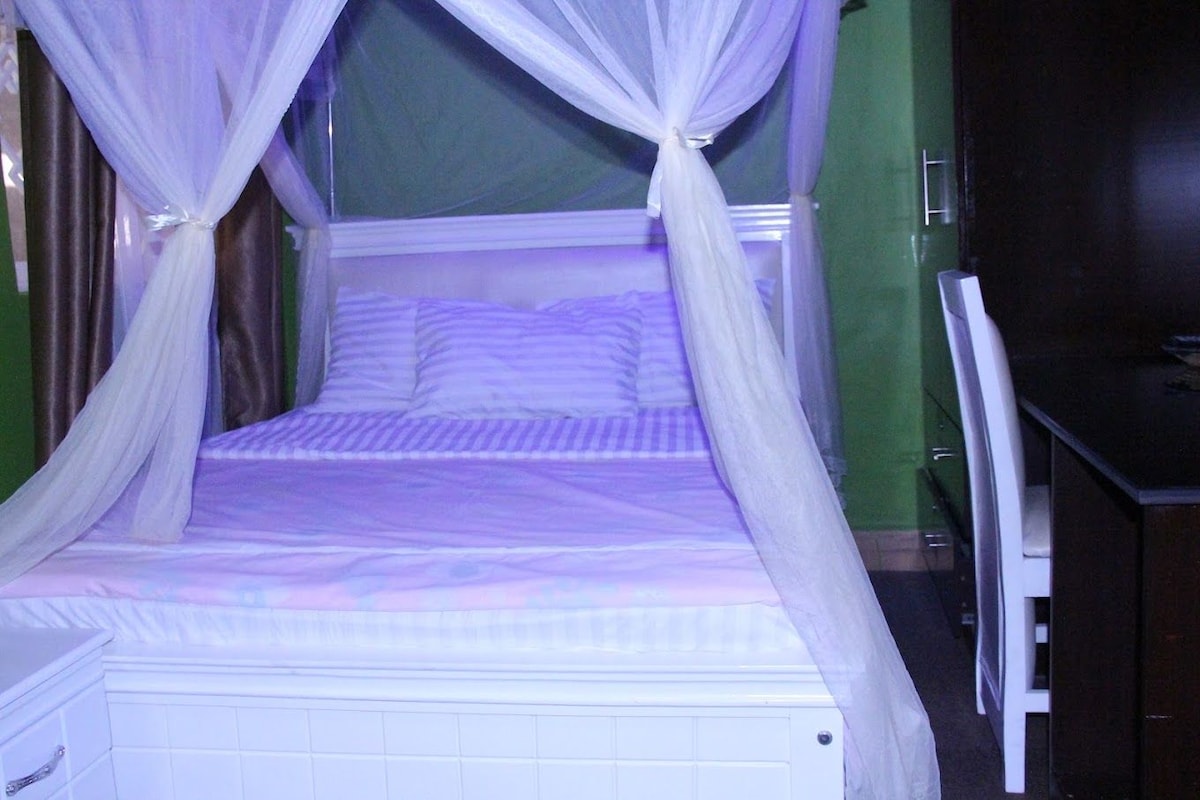 Una cama con dosel, una mesita de noche y una silla.