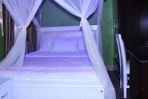 Una cama con dosel, una mesita de noche y una silla.