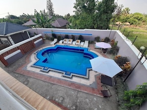 Una piscina con borde azul, rodeada de sillas de descanso y sombrillas.