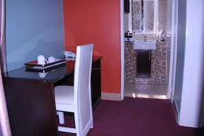 Habitación compacta con escritorio, silla y kitchenette.