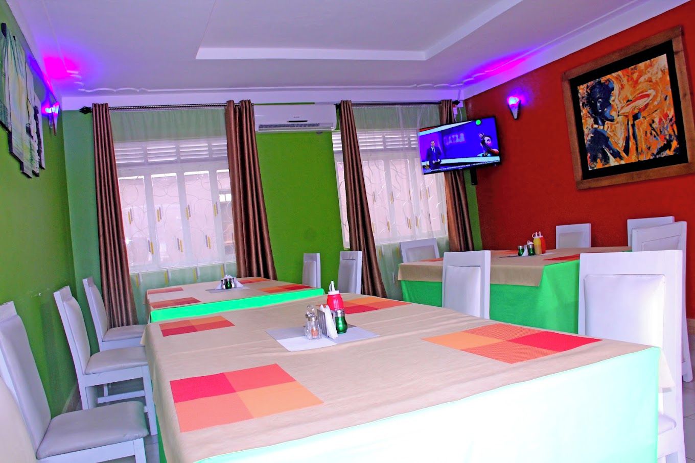 A conference room with a large table, chairs, a television, and a painting on the wall.