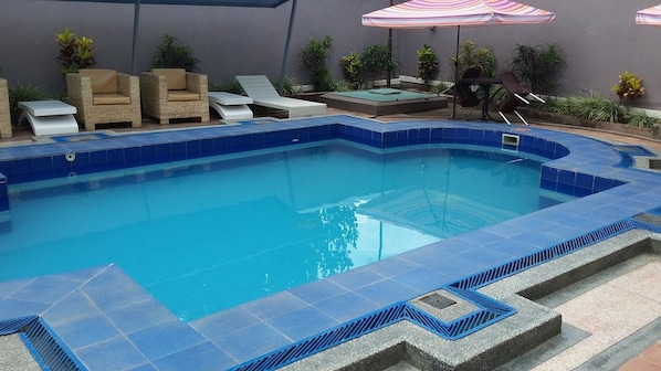 A swimming pool with lounge chairs and umbrellas.