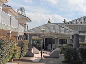 A residential building with a covered patio, steps leading to the entrance, and a street lamp.