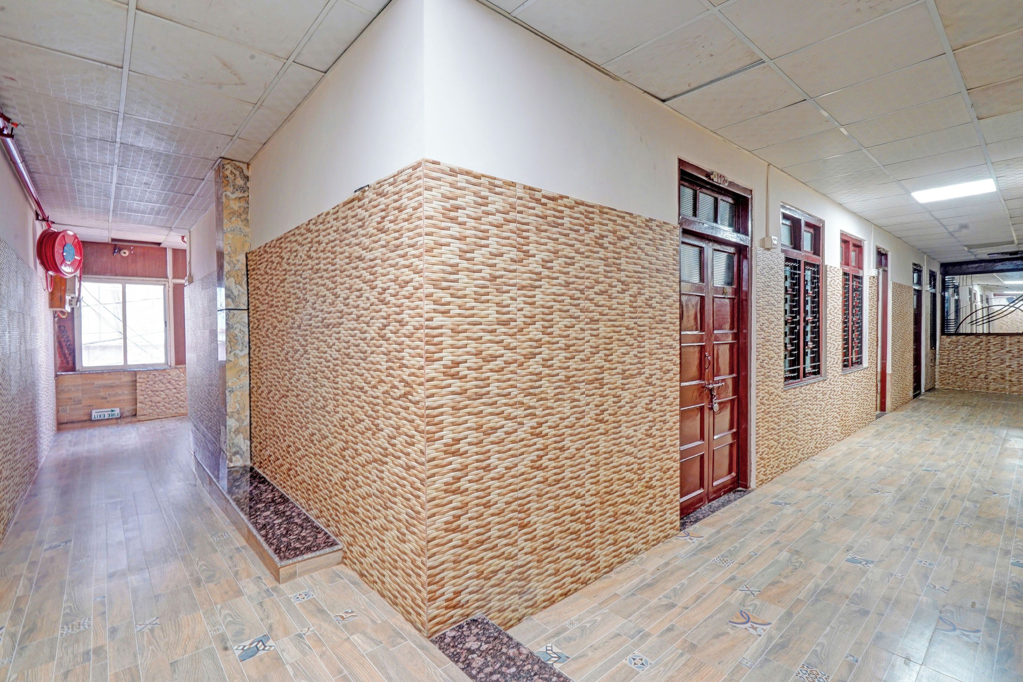 A hallway with a textured wall, a fire hose reel, and a tiled floor.