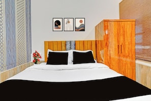 A bedroom with a bed, a wooden wardrobe, and three framed pictures on the wall. - Hotel O Daltonganj Bus Stand (Daltonganj)