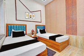 A hotel room with two beds, a nightstand, a vase with flowers, and a patterned wall. - Hotel O Daltonganj Bus Stand (Daltonganj)