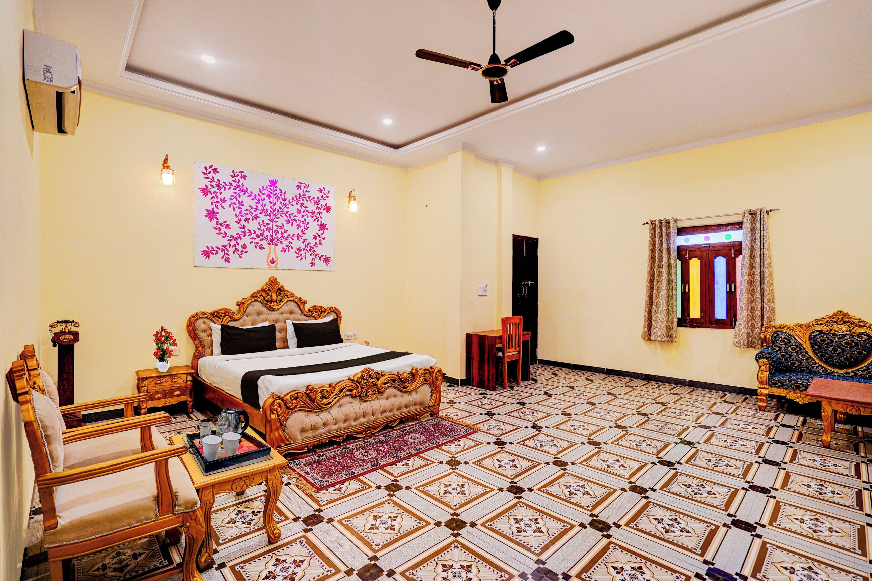 A hotel room with a large bed, a ceiling fan, a decorative wall piece, a patterned floor, and a window with curtains.