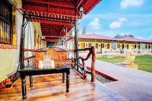 A traditional wooden bench with a table, a hanging lantern, and a statue of a horse.
