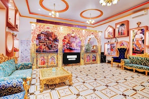A room with a patterned floor, a sofa, a table, and a decorative wall with artwork. - Super OYO Palette Hotel and Resort LBS (Pindra)
