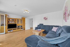 Ein modernes Wohnzimmer mit einem blauen Sofa, einer Holz-Unterhaltungseinheit und einem Flachbildfernseher.