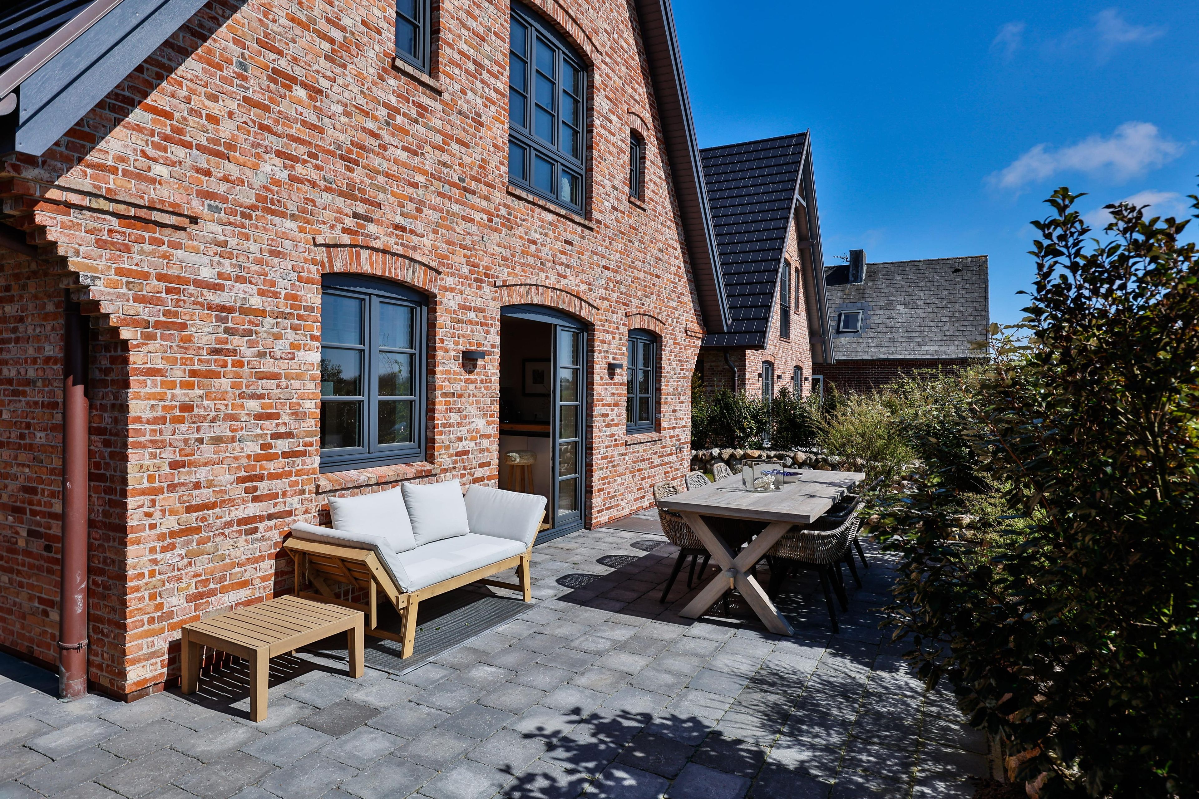 Ein Backsteinhaus mit einer Terrasse, einem Sofa und einem Tisch.