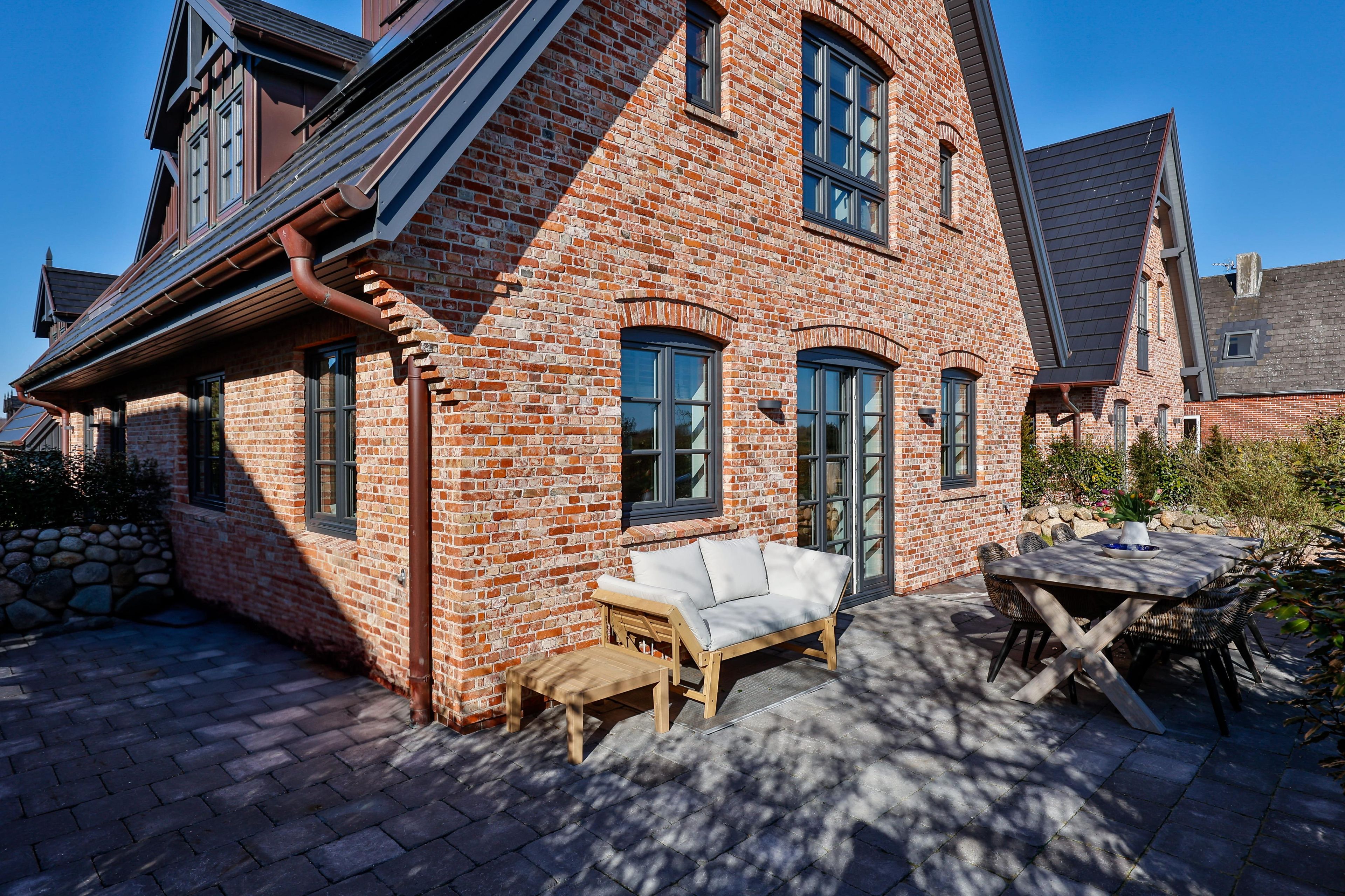 A brick house with a patio area, a wooden bench, and a table.