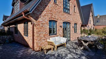 A brick house with a patio area, a wooden bench, and a table.