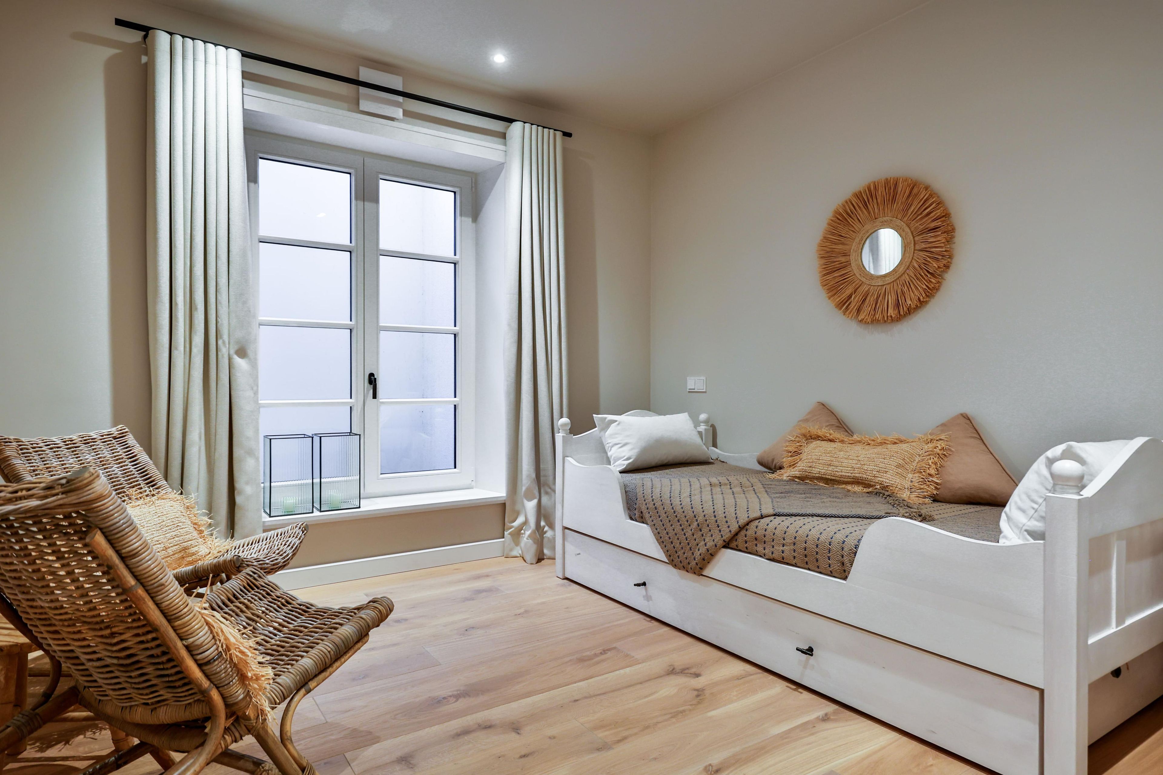 A bedroom with a bed, a chair, a window, and a wall decoration.
