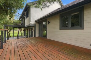 A two-story house with a wooden deck, a balcony, and a large window. - Wooded golf Course Retreat (Westerville)