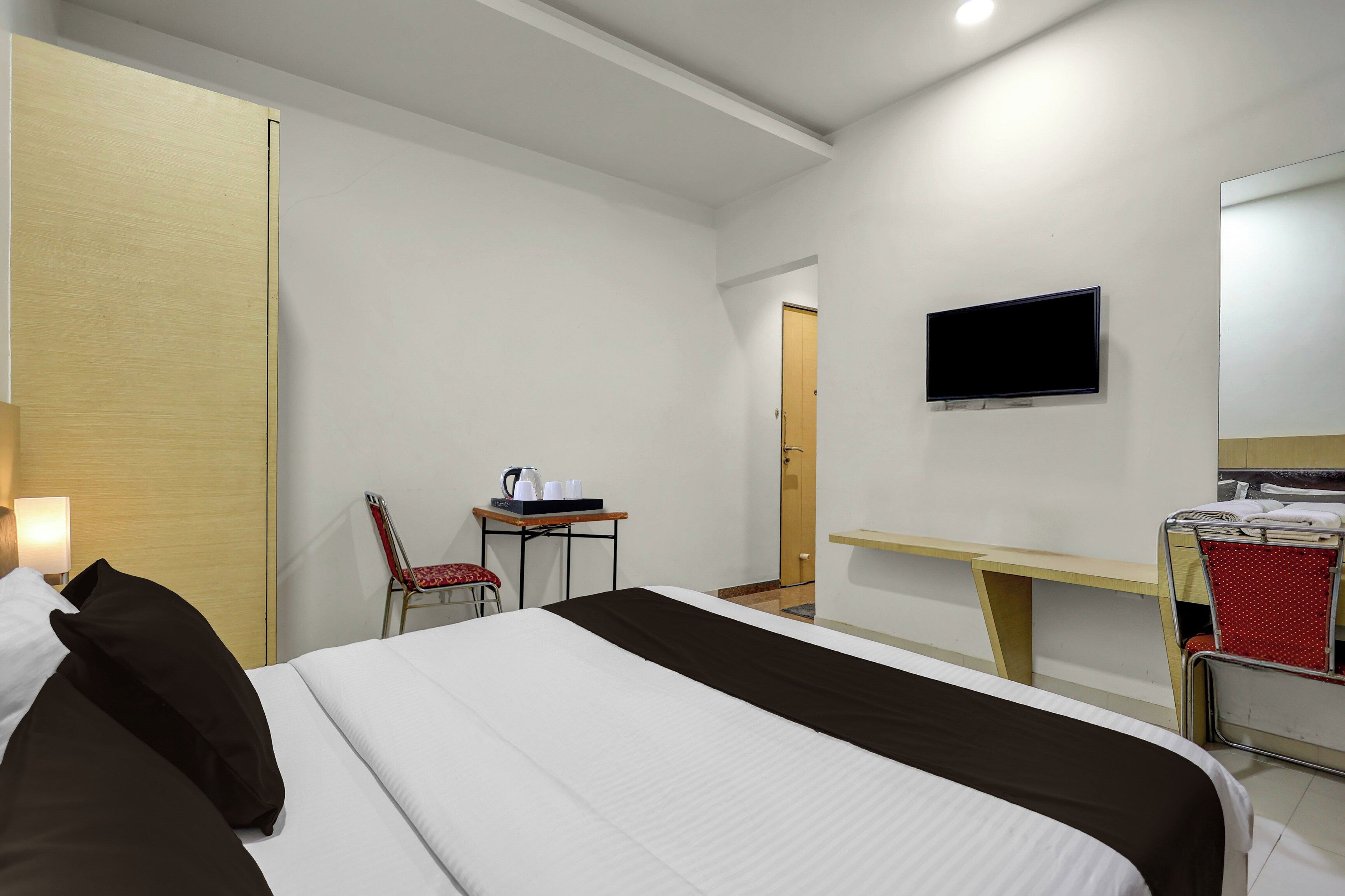 Een hotelkamer met een bed, een bureau met stoel, een televisie en een deur naar de badkamer.