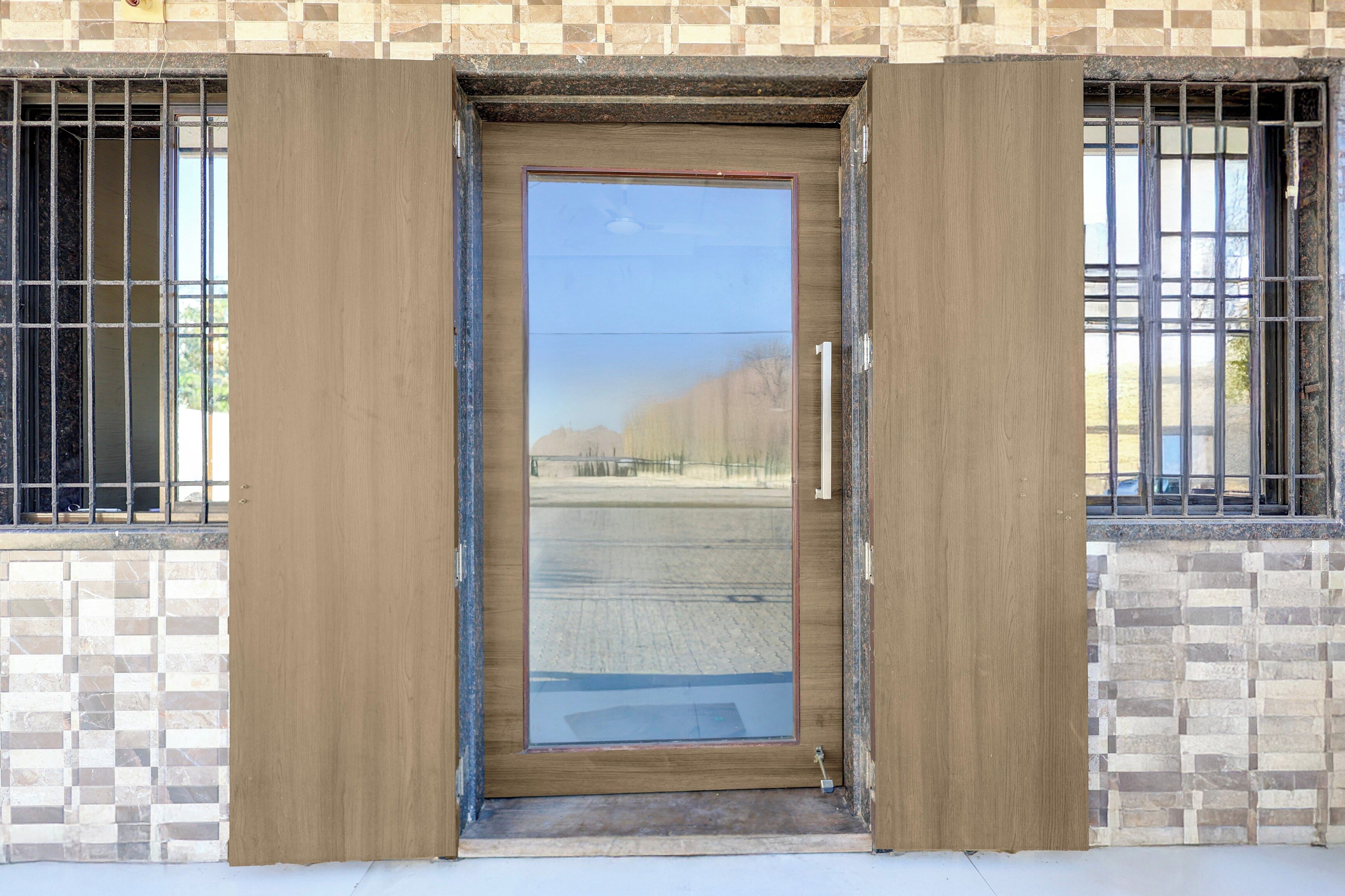 Una puerta de madera con un panel de vidrio, en un edificio con paredes de azulejos y ventanas con barrotes.