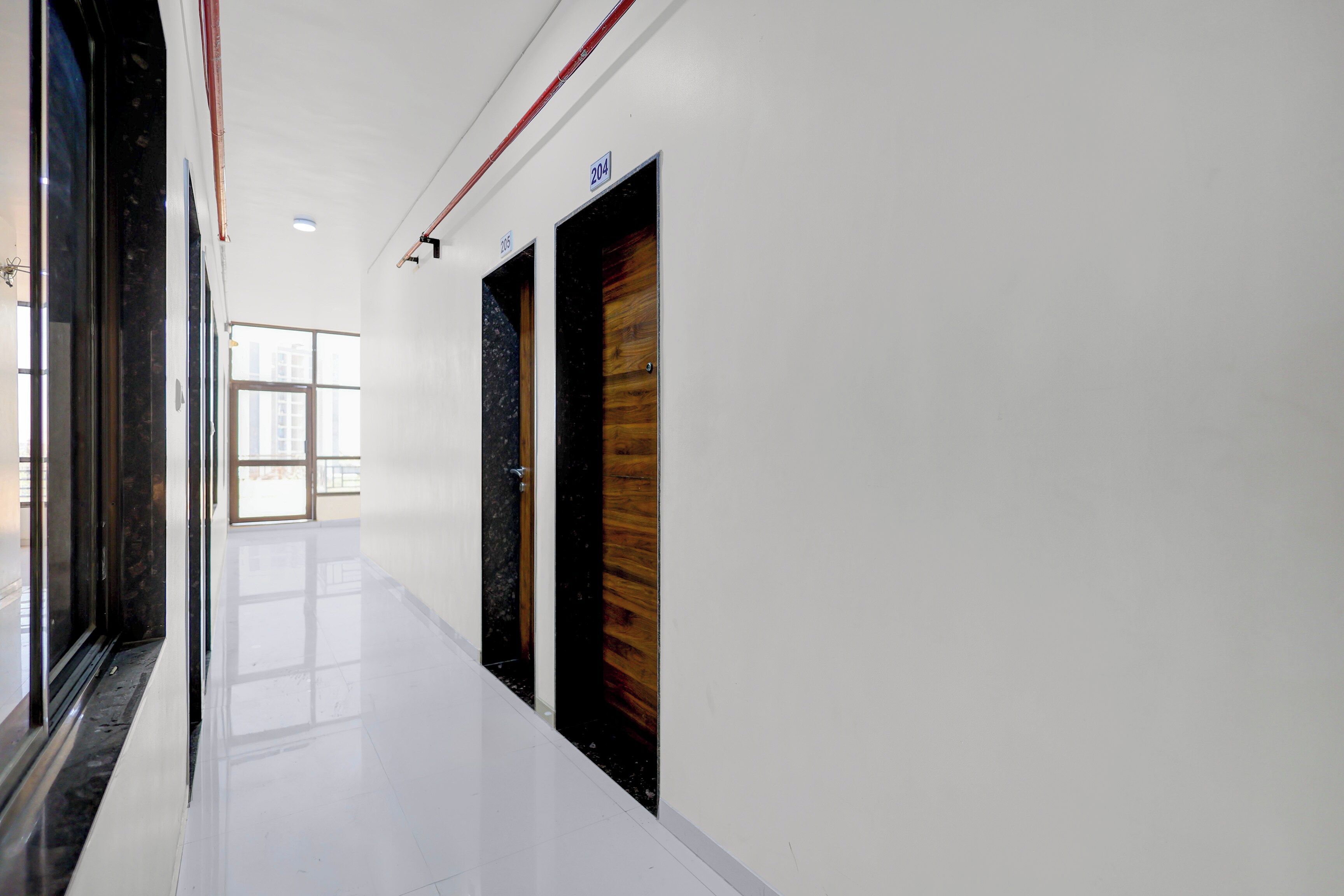 A corridor with white walls, a shiny floor, and doors with numbers 204 and 205.