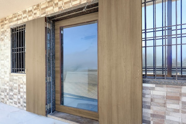A building entrance with a glass door, a window with metal bars, and a tiled wall.