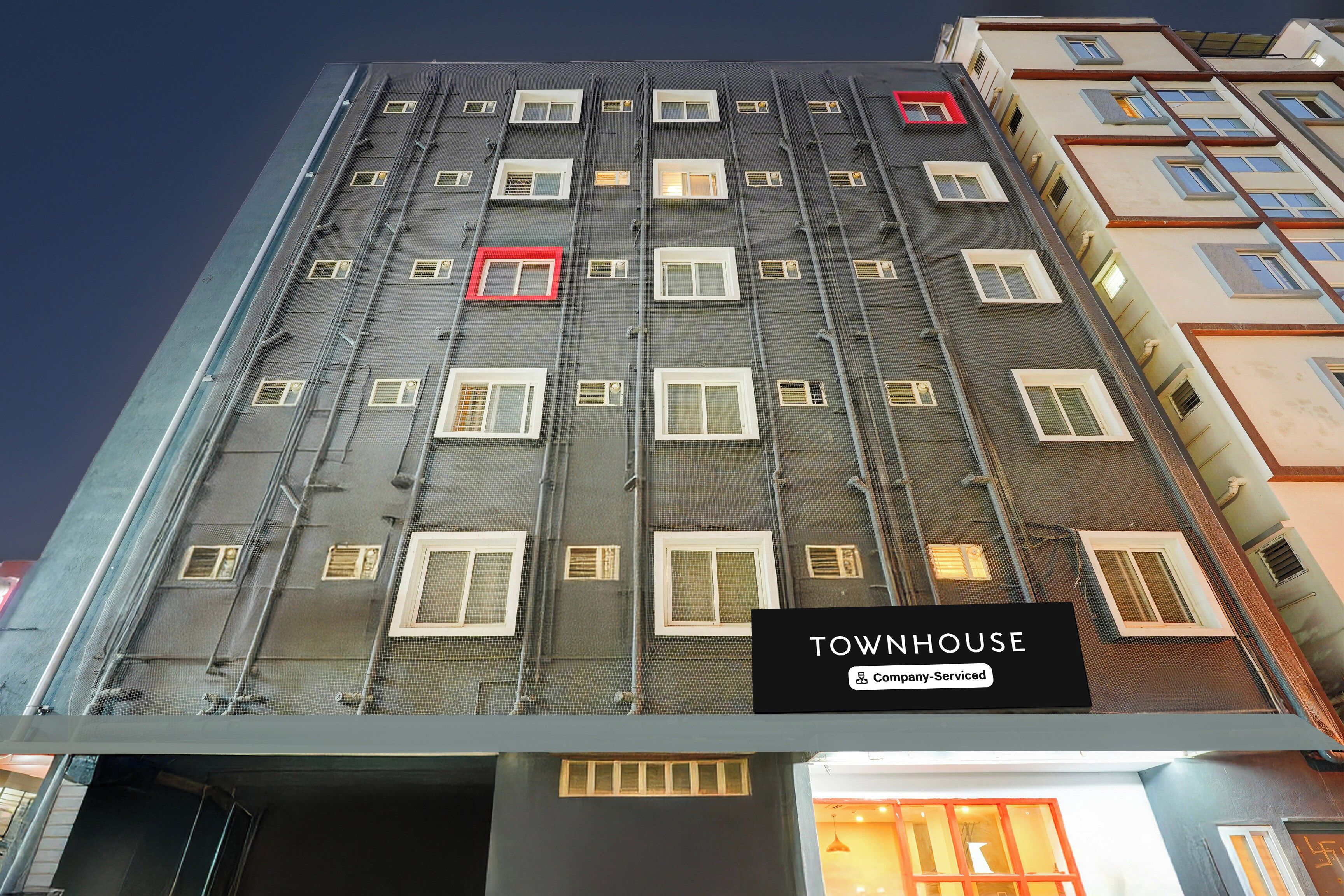 A multi-story building with a sign indicating it is a company-serviced townhouse.