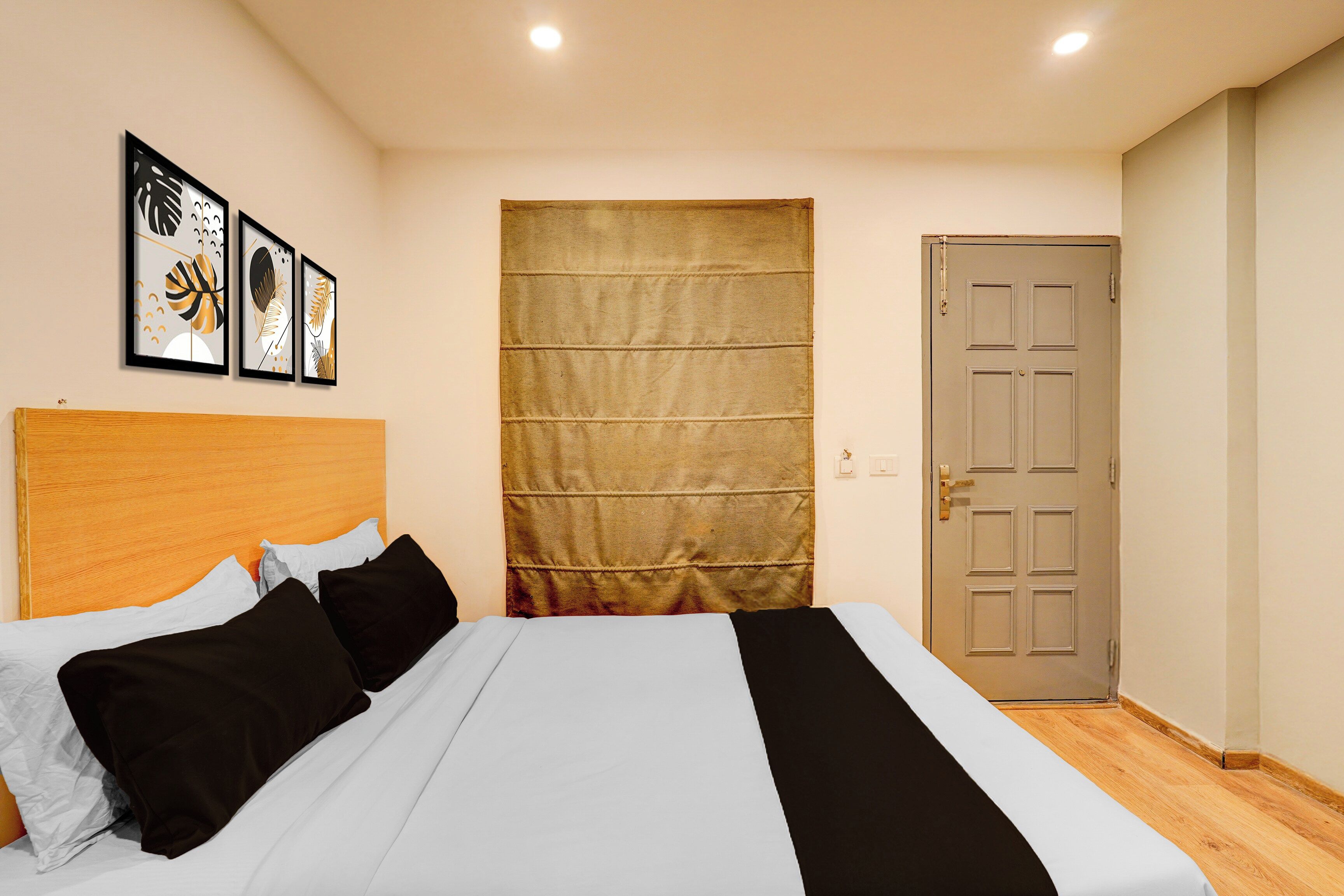 Un dormitorio con cama, cabecera, puerta y pared decorada con cuadros.