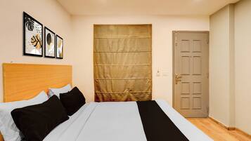Un dormitorio con cama, cabecera, puerta y pared decorada con cuadros.