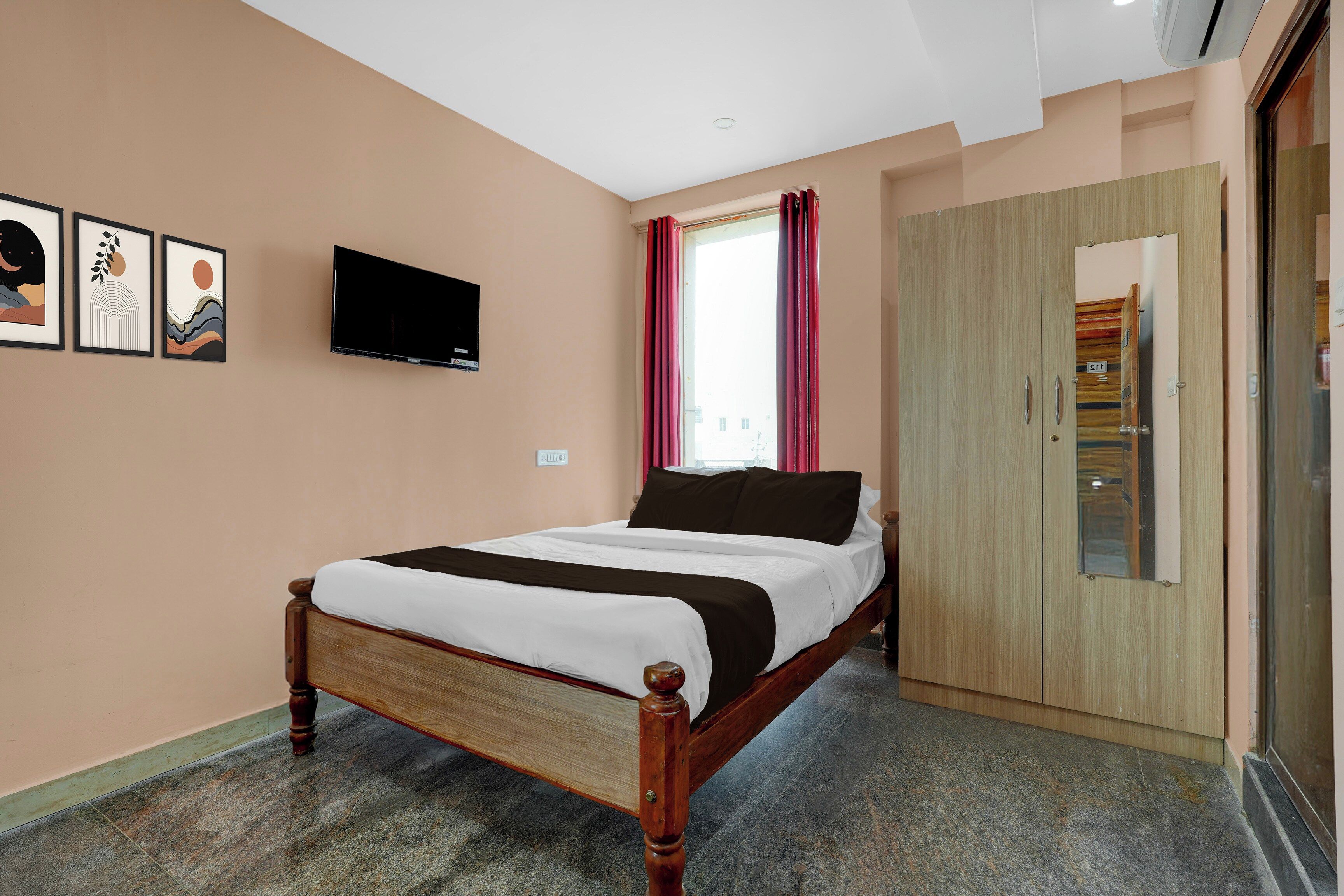 Een slaapkamer met een bed, een televisie, een kledingkast en een raam met gordijnen.