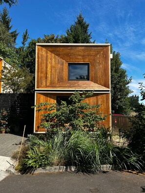 A two-story wooden building with a central window and a balcony. - Mt. Tabor Guesthouse | Courtyard & Park Walk (Portland)