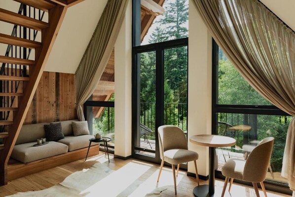 A modern interior with a wooden staircase, a sofa, a round table, and chairs.