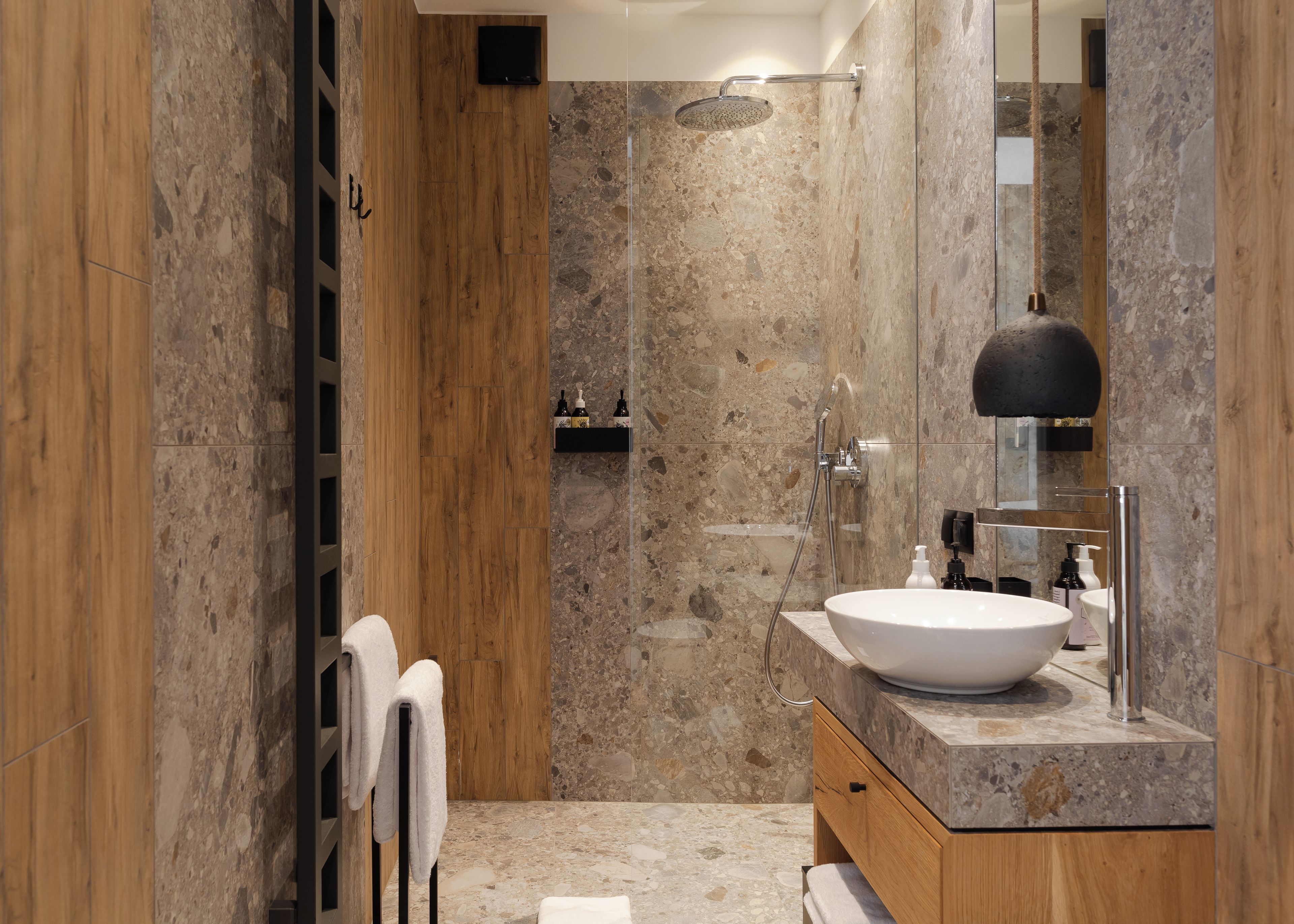 A modern bathroom with a large sink, a shower, and a mirror.
