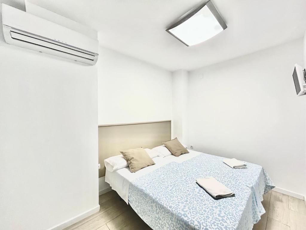 Un dormitorio con cama, mesita de noche y aire acondicionado de pared.