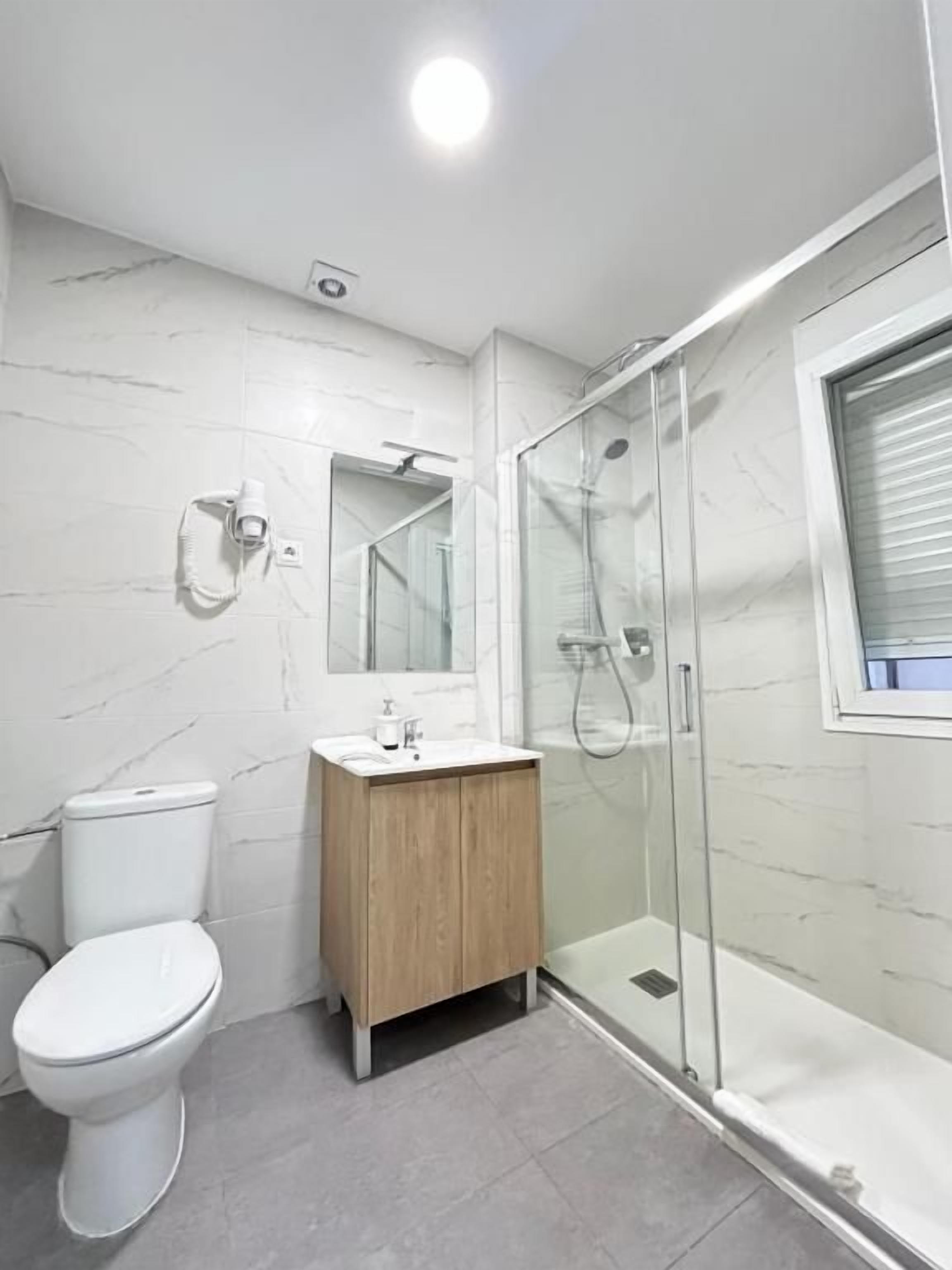 Un baño moderno con inodoro, lavamanos y ducha envuelta en vidrio.
