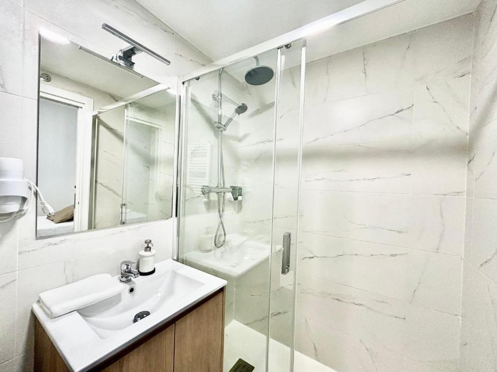 A bathroom with a glass-enclosed shower, a white sink, and a mirror above the sink.