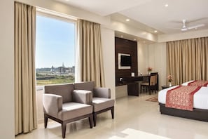 Una habitación de hotel con un ventanal grande, un sofá, un escritorio y una cama.