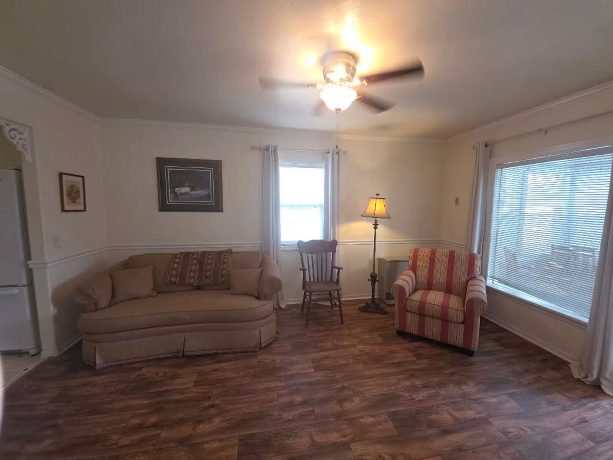 Living room with a curved sofa, striped armchair, and wood-look flooring.