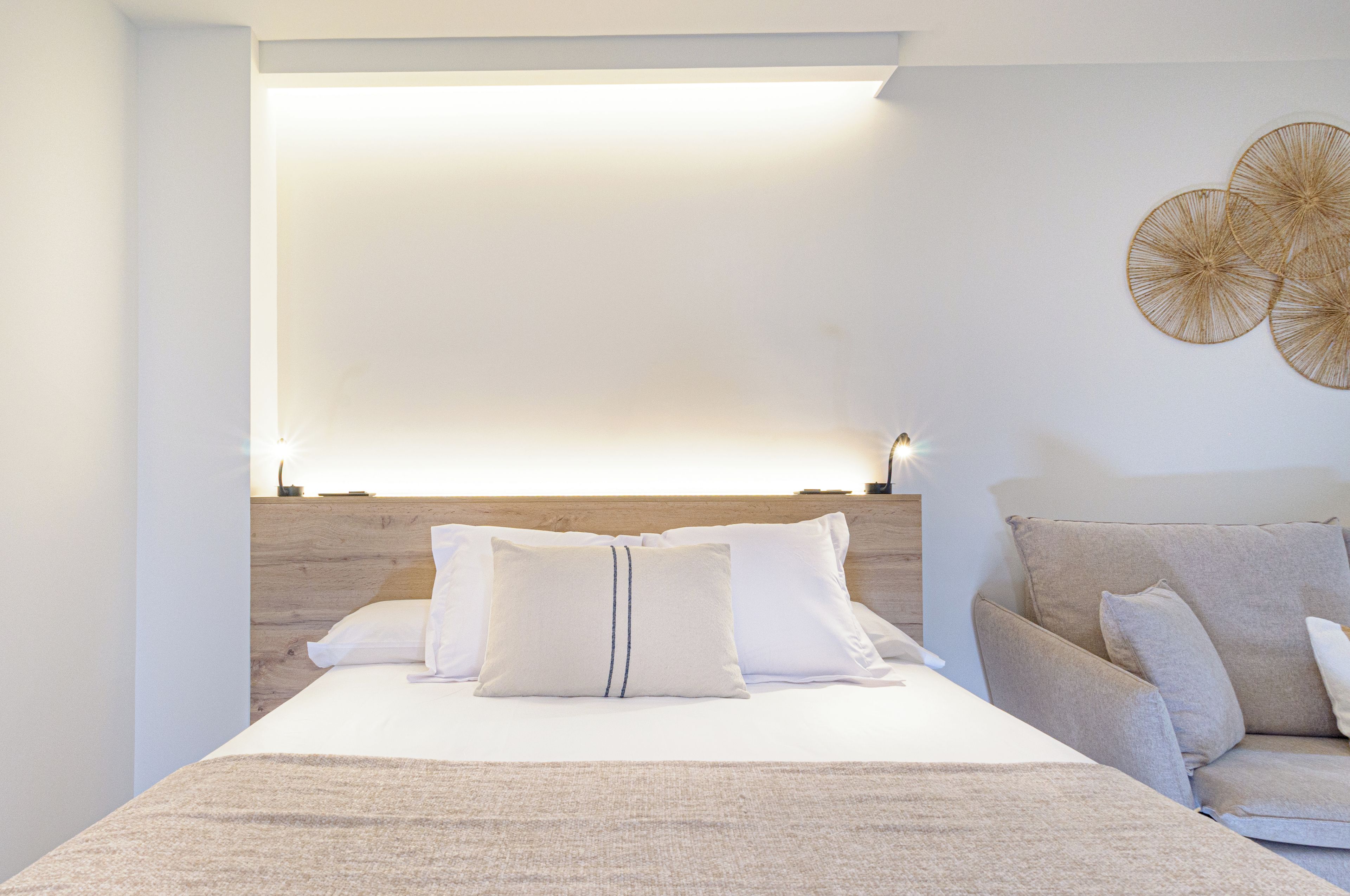 Ein modernes Schlafzimmer mit Bett, einer Couch und einer Wandleuchte.