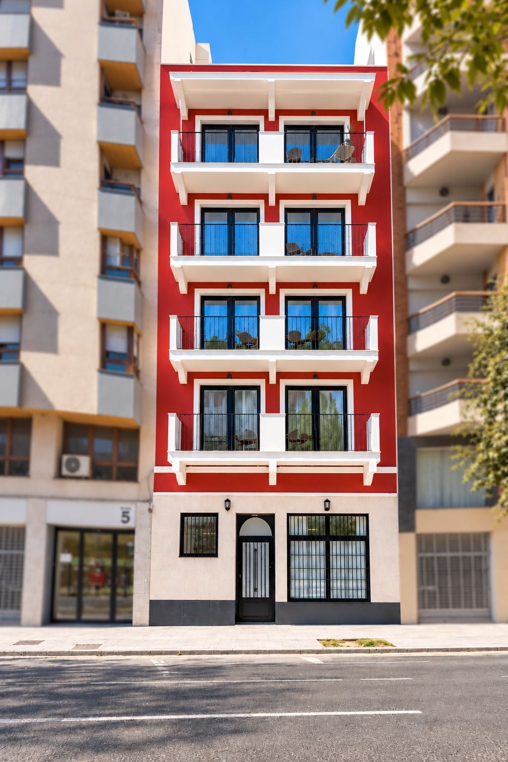 Un immeuble résidentiel à plusieurs étages, doté de balcons, d’une façade sobre et surplombant un ciel dégagé.