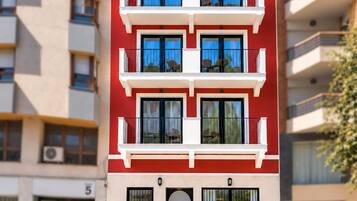 Un immeuble résidentiel à plusieurs étages, doté de balcons, d’une façade sobre et surplombant un ciel dégagé.