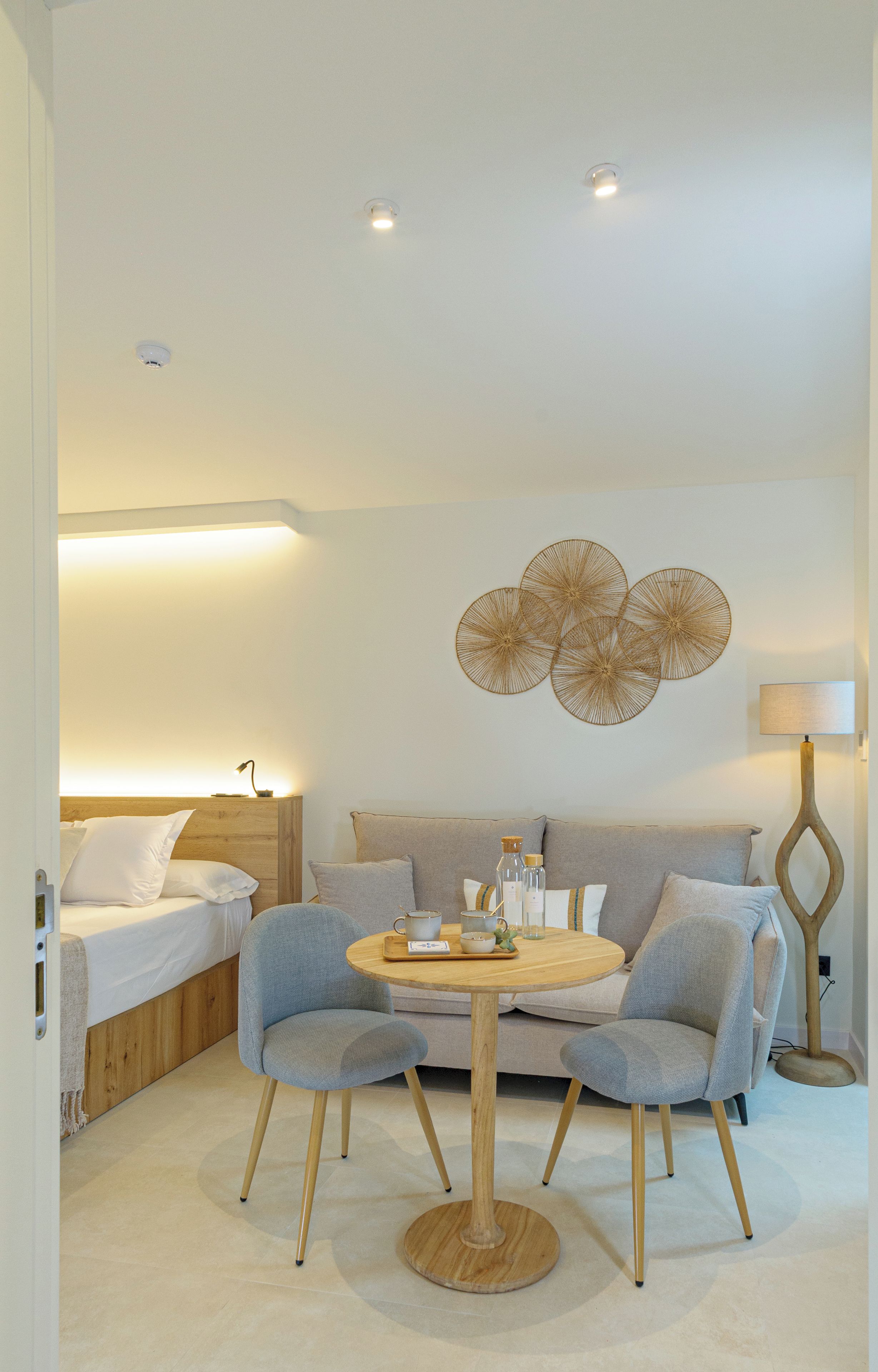 Ein modernes Hotelzimmer mit einem Bett, einer Couch, zwei Sesseln, einem runden Holztisch und einer Wanddekoration.