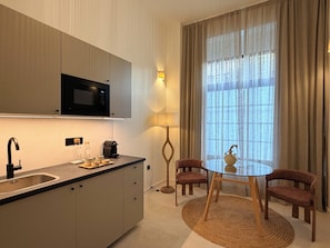 A modern kitchen with a microwave, coffee maker, and a dining area with a table and chairs. - Alma House (Alacant)