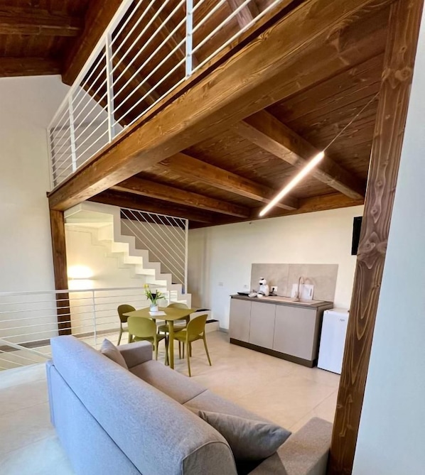 A modern interior with a dining area, kitchen, and a staircase leading to an upper level.