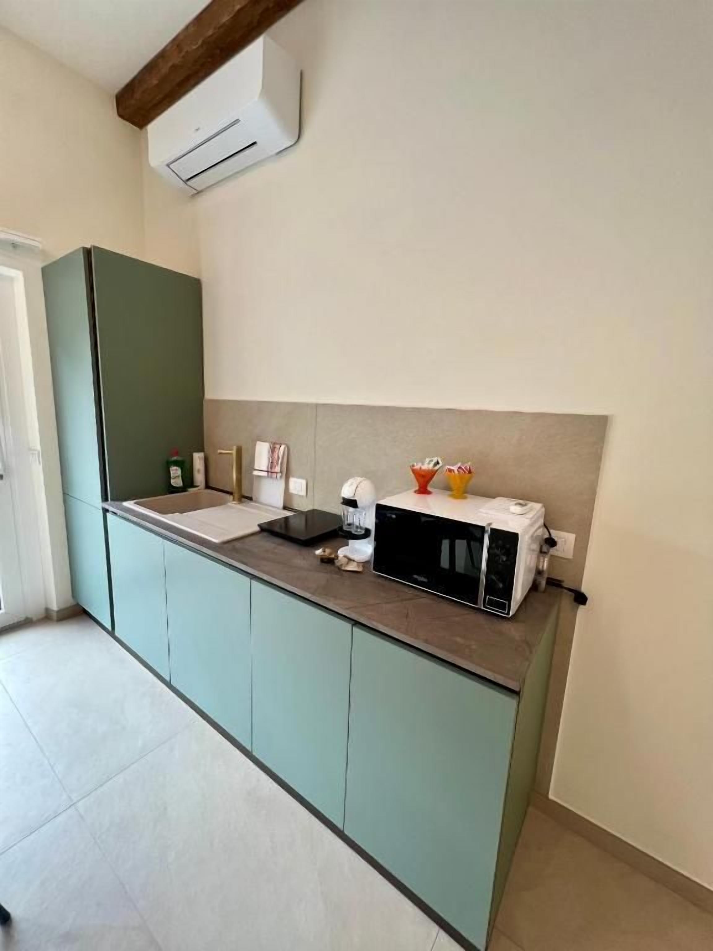 A kitchen with a built-in microwave, a sink, and a countertop with a toaster and a kettle.