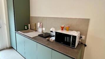 A kitchen with a built-in microwave, a sink, and a countertop with a toaster and a kettle.